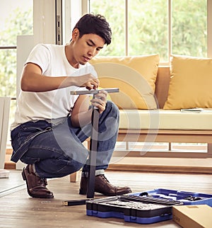 Asian man trying to assemble knockdown furniture