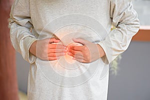 Asian man two hands touching stomach because of abdominal pain cause is from stomach disease or indigestion and enteritis or photo