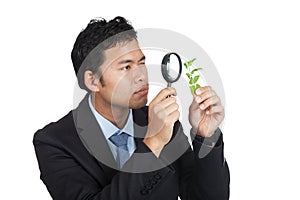 Asian man use magnifying glass observe leave