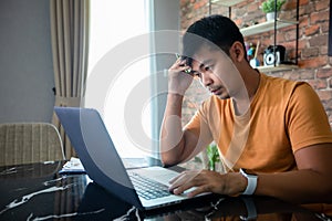 Asian man uses a notebook computer and works hard and meeting at home and he is stressed and Headache