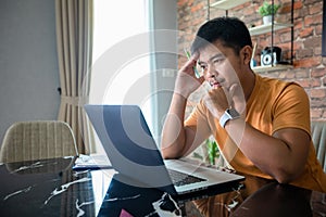 Asian man uses a notebook computer and works hard and meeting at home and he is stressed and Headache