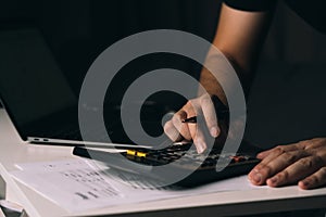 Asian man is using a calculator to calculate his family's monthly miscellaneous expenses at his home