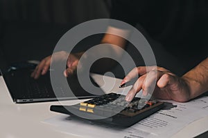 Asian man is using a calculator to calculate his monthly miscellaneous expenses at home