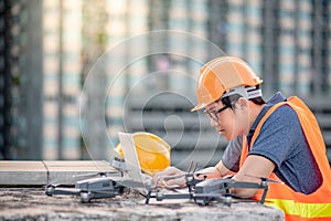 Asian man using drone and laptop for construction site survey