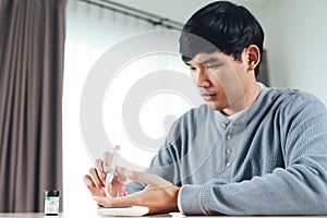 Asian man using lancet on finger for checking blood sugar level by Glucose meter, Healthcare and Medical, diabetes, glycemia