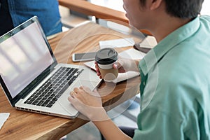 Asian man using laptop in coffee shop