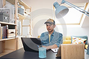 Asian man using laptop while working in a home office