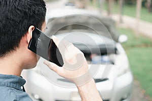 Asian man using mobile phone calling for assistance after a car breakdown on street. Concept of vehicle engine problem or accident