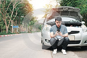 Asian man using mobile phone calling for assistance after a car breakdown on street. Concept of vehicle engine problem or accident