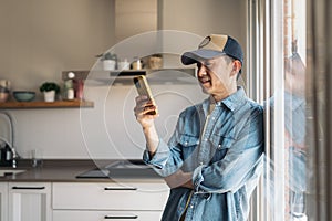 Asian man using mobile standing at home