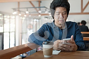 Asian man using phone in coffee shop