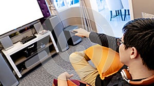 Asian man using remote controller while watching TV