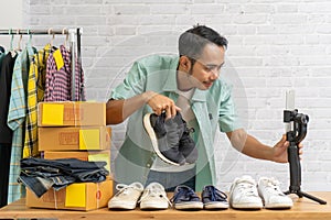 Asian man using smart mobile phone taking live selling shoes online