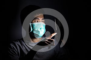 Asian man using smart phone work from home and wear a protective medical mask to prevent Coronavirus CoVID-19 outbreak