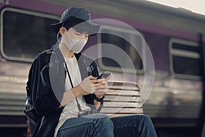 Asian man using smartphone with medical face mask to protect the Covid-19, new normal lifestyle