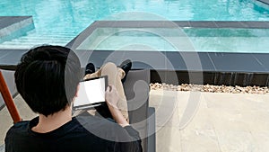 Asian man using tablet near swimming pool