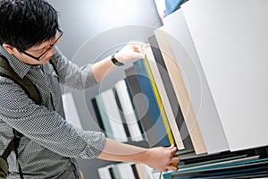 Asian man using tape measure on cabinet materials