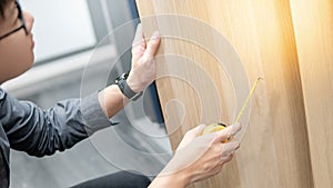 Asian man using tape measure on cabinet materials