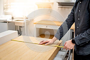 Asian man using tape measure on countertop