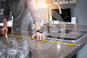 Asian man using tape measure on kitchen counter