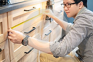 Asian man using tape measure on kitchen counter