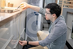 Asian man using tape measure on kitchen counter