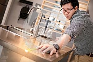 Asian man using tape measure on kitchen counter