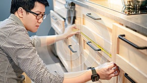 Asian man using tape measure on kitchen counter