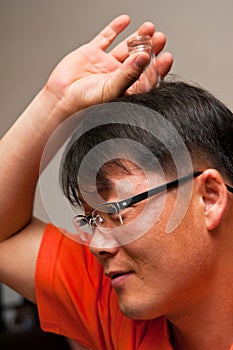 Asian man with vodka glass on his head