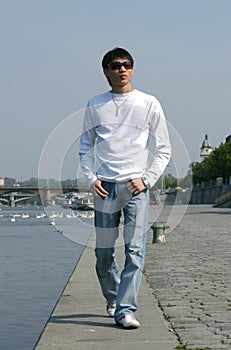 Asian Man Walking along the Embankment