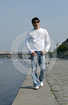 Asian Man Walking along the Embankment