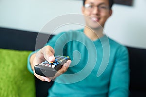 Asian Man Watching TV Changes Channel With Remote