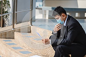 Asian man wear a mask searches Looking for a job with male person considering job vacancies sitting on the stairs, Concept of the