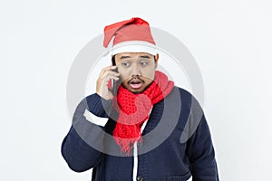 Asian man weared blue sweater, santa hat, red scarf using mobile phoe calling photo