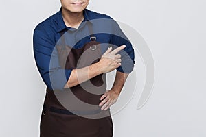 Asian Man wearing Apron pointing at something on the right, isolated