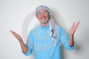 Asian man wearing Arabian shemagh head scarf open his arms with happy expression