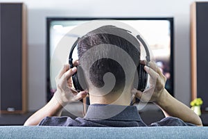 Asian man wearing black headphones enjoying home entertainment