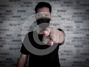 Asian man wearing black protective face mask and black shirt on dark background