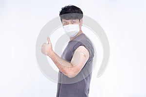 Asian man wearing face mask show thumps up and shoulder with bandage after getting vaccination covid-19 immunization,   on