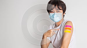Asian man wearing face mask with a smile on his face showing his vaccinated arm. fight against virus covid-19 coronavirus,