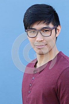 Asian man wearing glasses on a blue background - Stock image