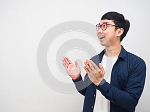 Asian man wearing glasses feeling happy and smile looking at copy space and show hand up