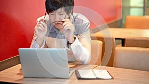 Asian man wearing glasses while using laptop