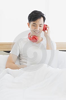 Asian man wearing red headphone, listening music