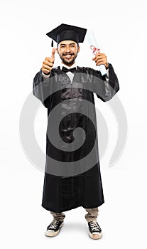 Asian man wearing toga with thumbs up holding diploma paper