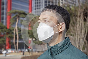 Asian man in white mask on the background of the city, the concept of air pollution