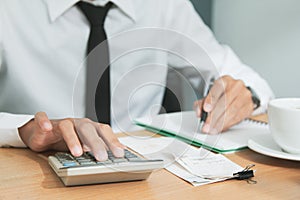 Asian man in white shirt holding pen writing a tax report lead to liquidation and using calculator