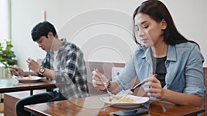 Asian man and woman having lunch meal in local restaurant, sit in social distance. Business reopening, social distancing culture