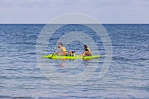 Asian man and woman with his dog in a kayak swims on the sea near island Koh Samet, Thailand