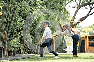 Asian Man and woman taking a pre wedding photo with woman grabbing his shoulder and bracing the man in the garden